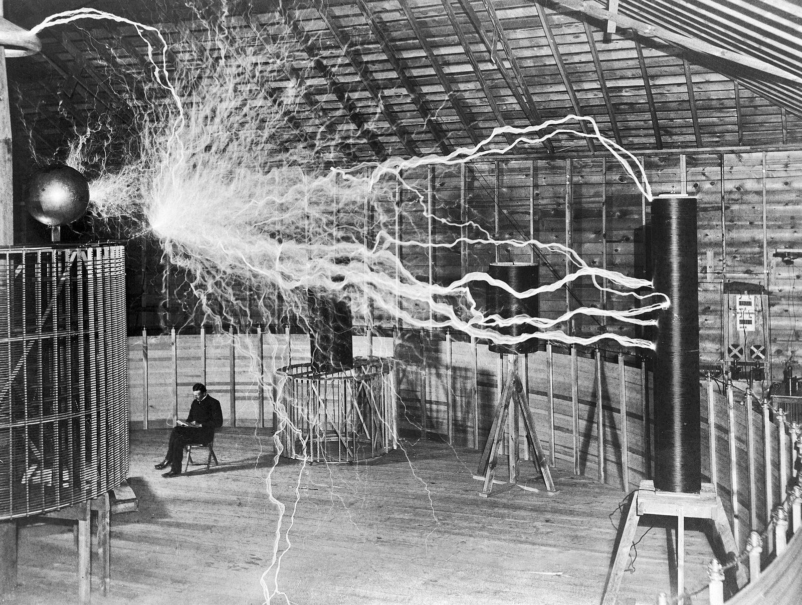 Nikola Tesla dans son laboratoire de Colorado Springs en 1899, assis au milieu de décharges électriques
