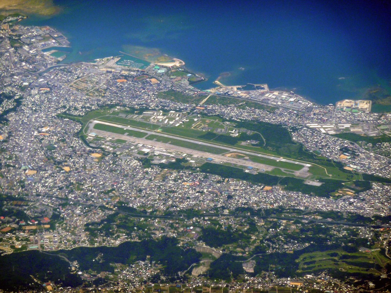 Aerial view of Marine Corps Air Station Futenma in Ginowan, Okinawa, surrounded by dense residential neighborhoods